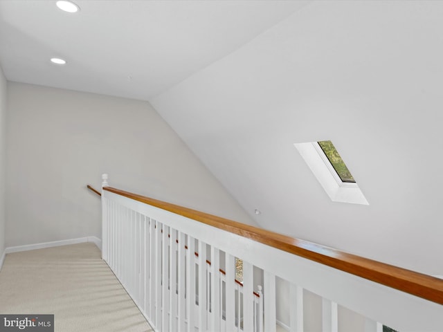 hall featuring vaulted ceiling and light colored carpet