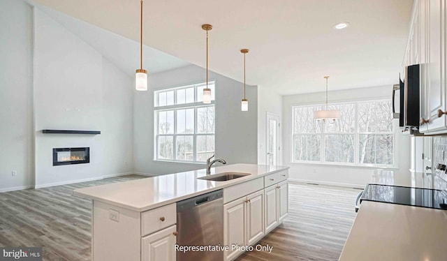 kitchen featuring appliances with stainless steel finishes, white cabinetry, light wood-type flooring, a kitchen island with sink, and sink