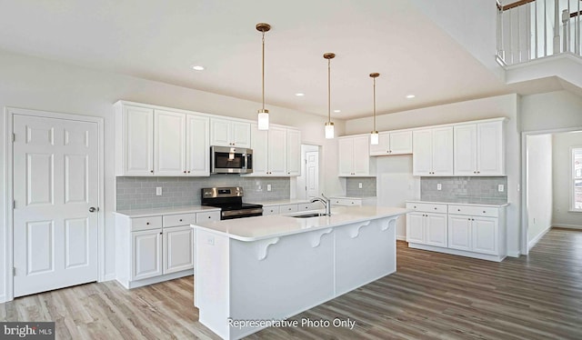 kitchen with white cabinets, stainless steel appliances, and light wood-type flooring