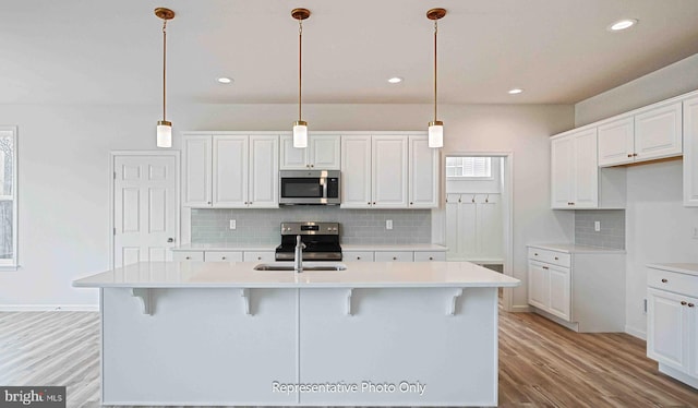 kitchen with an island with sink, light wood-type flooring, white cabinetry, and appliances with stainless steel finishes