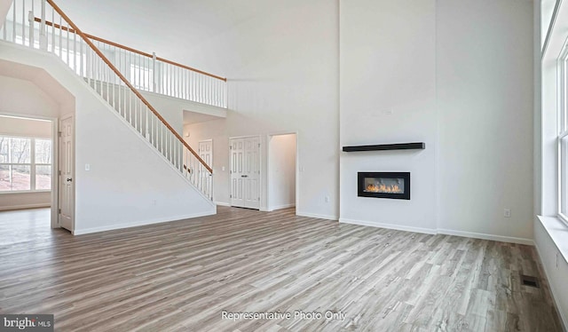 unfurnished living room featuring light hardwood / wood-style flooring and a high ceiling