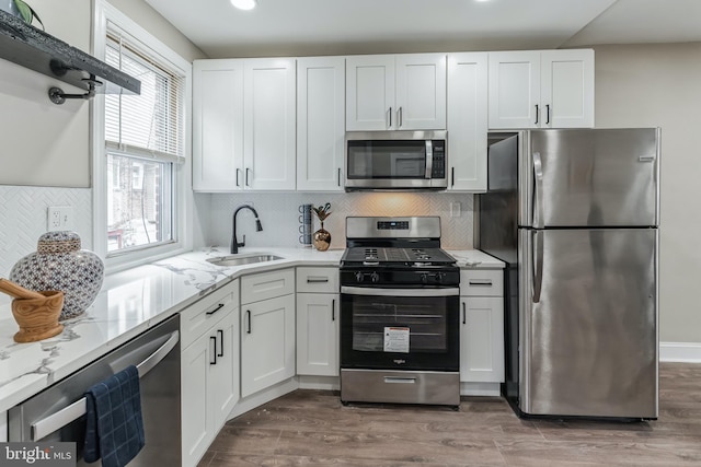 kitchen with appliances with stainless steel finishes, wood-type flooring, white cabinetry, and sink