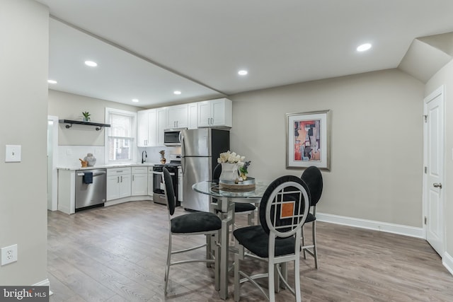 dining room with light hardwood / wood-style flooring and vaulted ceiling