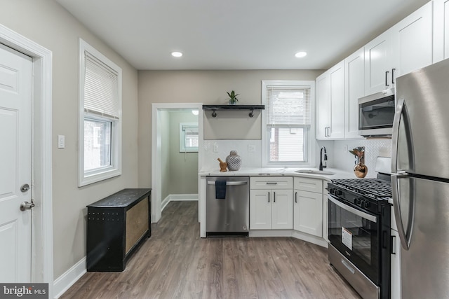 kitchen with white cabinets, sink, tasteful backsplash, wood-type flooring, and stainless steel appliances