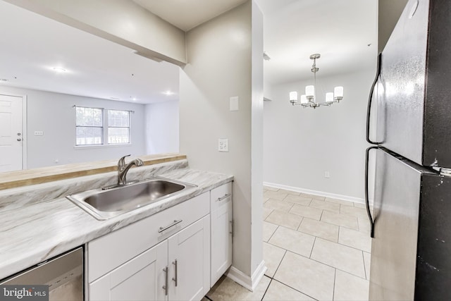 kitchen with sink, stainless steel appliances, pendant lighting, white cabinets, and a notable chandelier