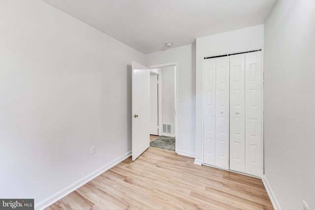 unfurnished bedroom featuring light hardwood / wood-style flooring and a closet