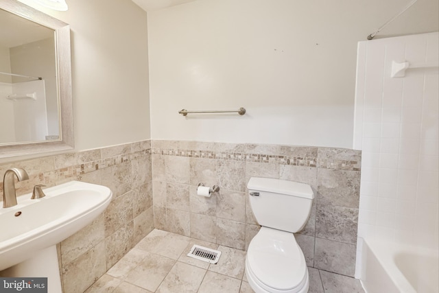 full bathroom with tile patterned floors, toilet, sink, tile walls, and washtub / shower combination