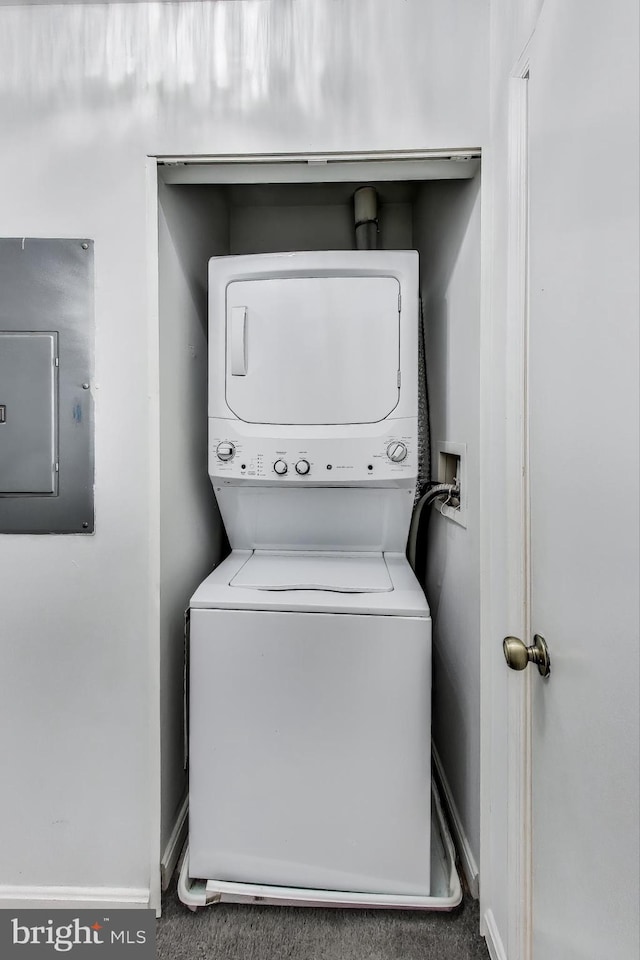 clothes washing area with dark carpet, electric panel, and stacked washer and dryer