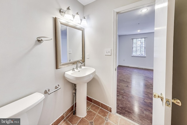 bathroom featuring toilet, sink, and wood-type flooring