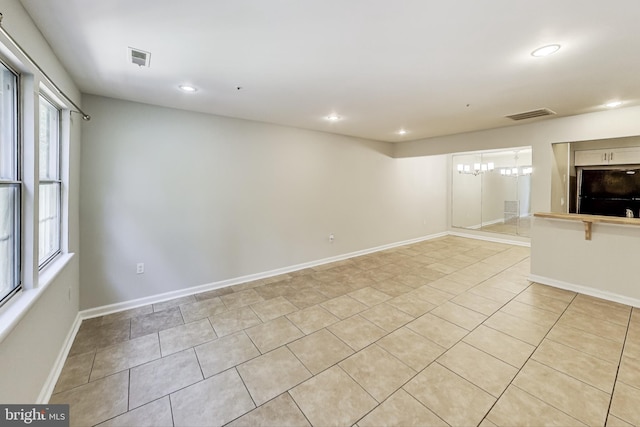 unfurnished living room with an inviting chandelier and light tile patterned floors