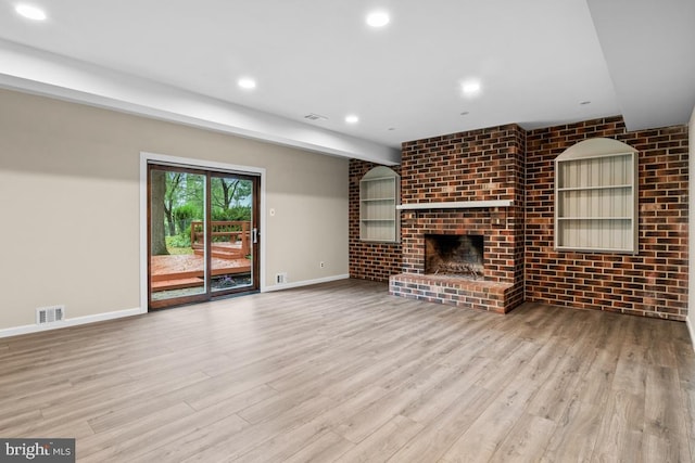 unfurnished living room featuring brick wall, light hardwood / wood-style flooring, and a fireplace