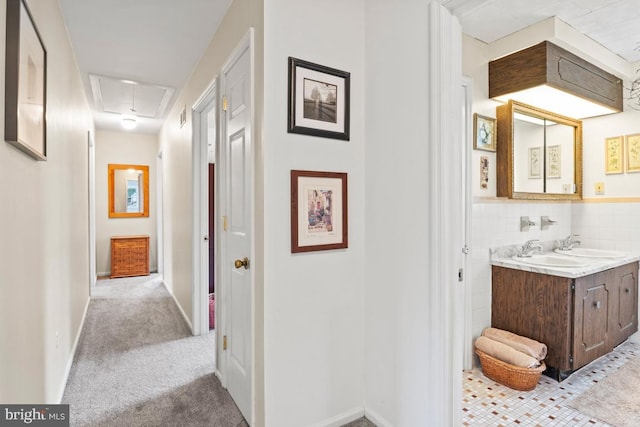 corridor featuring light colored carpet and sink