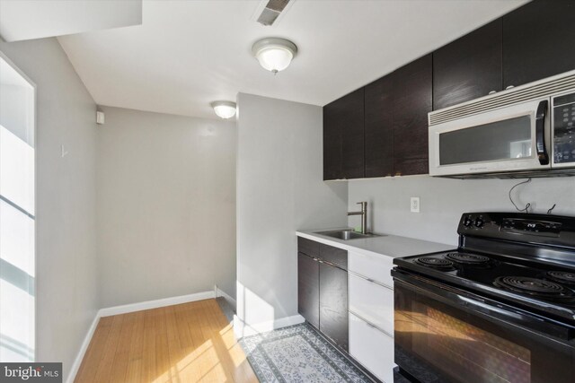 kitchen with sink, black electric range oven, and light hardwood / wood-style flooring