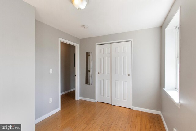 unfurnished bedroom with light hardwood / wood-style flooring and a closet