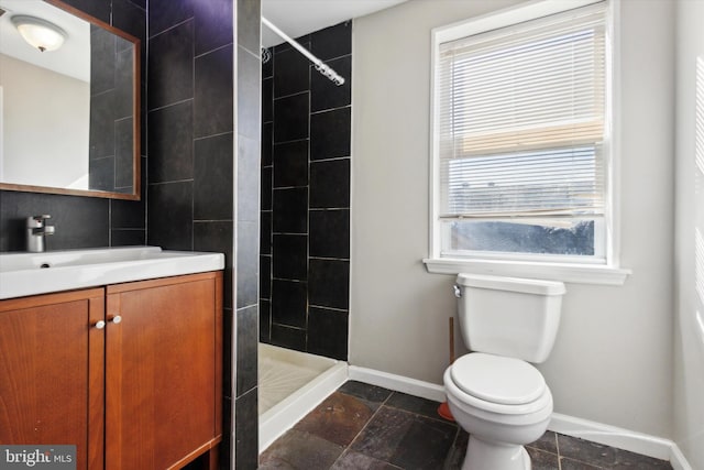 bathroom with vanity, toilet, and tiled shower