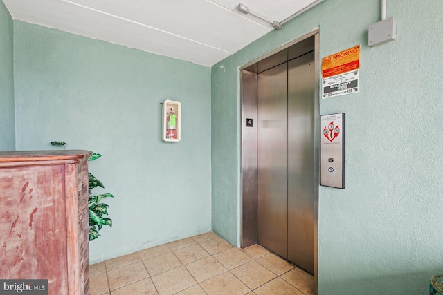 hall with elevator and light tile patterned floors