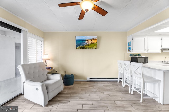 sitting room with light hardwood / wood-style floors, ceiling fan, a baseboard radiator, ornamental molding, and sink