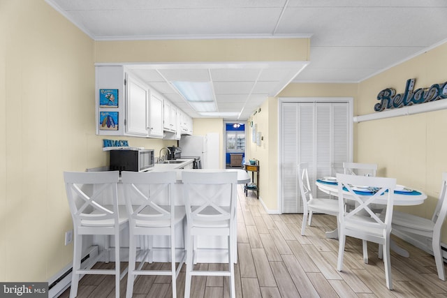 kitchen featuring a kitchen breakfast bar, white cabinets, kitchen peninsula, light hardwood / wood-style flooring, and sink