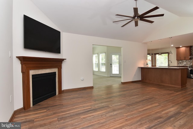 unfurnished living room with lofted ceiling, a wealth of natural light, and dark hardwood / wood-style floors