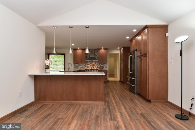 kitchen with kitchen peninsula, dark hardwood / wood-style floors, lofted ceiling, and wall chimney exhaust hood