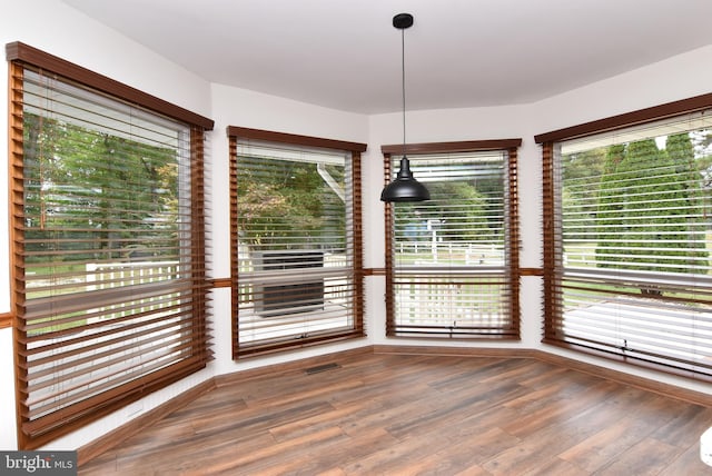 unfurnished dining area featuring a wealth of natural light and dark hardwood / wood-style floors