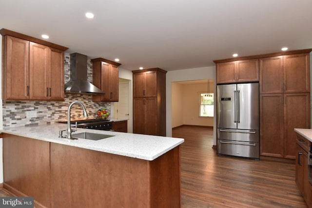 kitchen featuring light stone countertops, appliances with stainless steel finishes, sink, wall chimney exhaust hood, and dark wood-type flooring