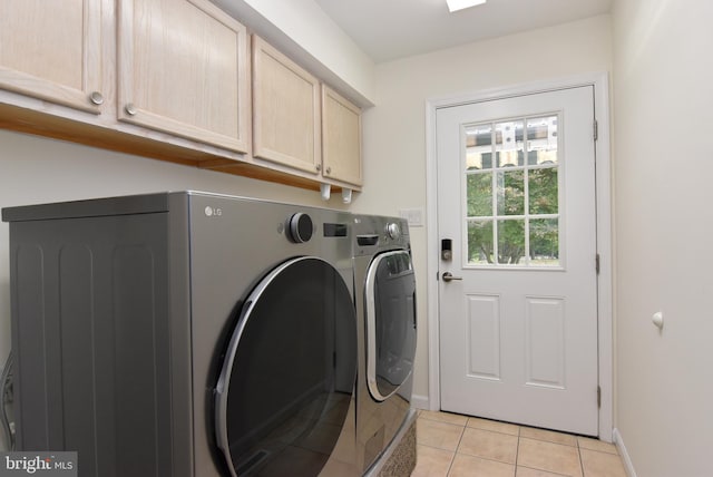 laundry room featuring cabinets, light tile patterned flooring, and washing machine and dryer