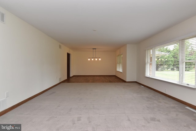 unfurnished room with a chandelier and light colored carpet