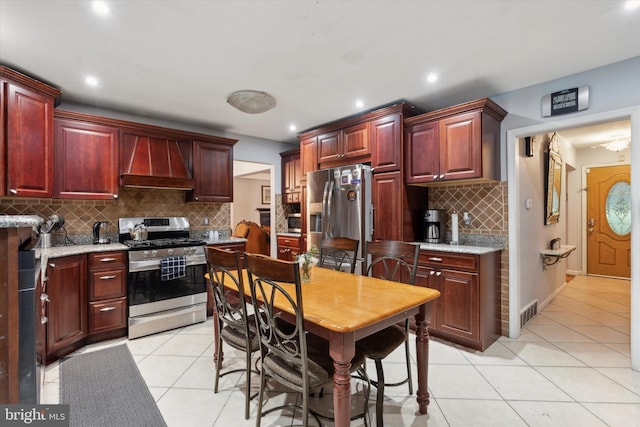 kitchen with stainless steel appliances, light tile patterned floors, custom range hood, and tasteful backsplash