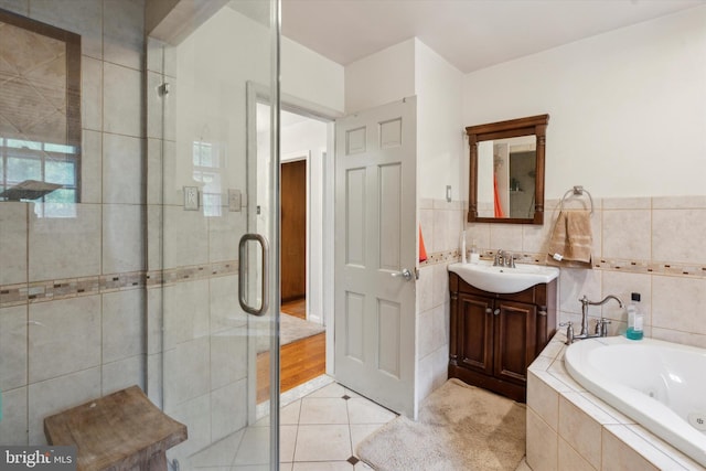 bathroom featuring plus walk in shower, tile walls, tile patterned floors, and vanity