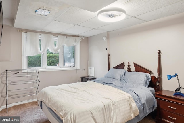 carpeted bedroom featuring a drop ceiling