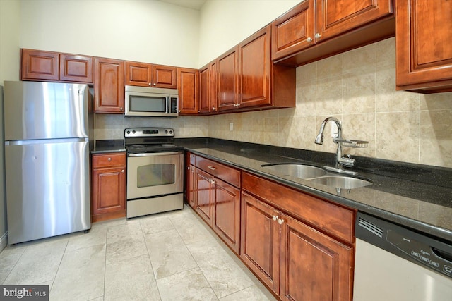 kitchen featuring appliances with stainless steel finishes, decorative backsplash, dark stone countertops, light tile patterned floors, and sink