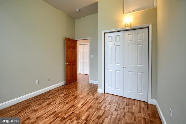 unfurnished bedroom with a closet, light hardwood / wood-style floors, and a high ceiling