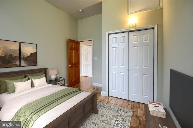 bedroom with a closet, a towering ceiling, and hardwood / wood-style floors