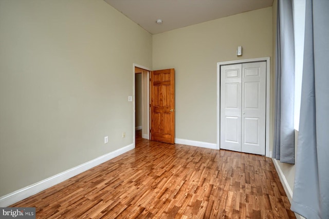 unfurnished bedroom featuring light hardwood / wood-style floors, a closet, and high vaulted ceiling