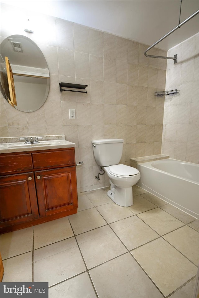 full bathroom with tile walls, tile patterned floors, vanity, tiled shower / bath, and toilet