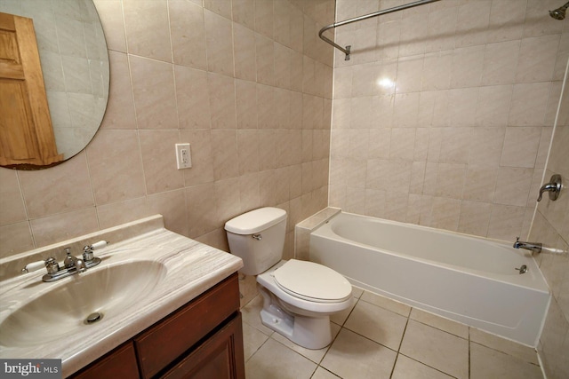 full bathroom with tile walls, tile patterned flooring, tiled shower / bath combo, vanity, and toilet