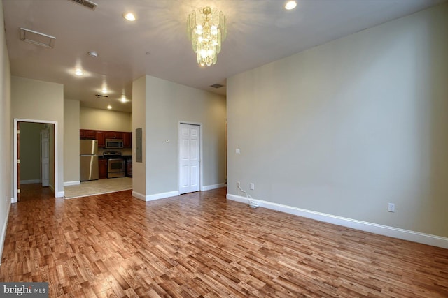 unfurnished living room with light hardwood / wood-style flooring and a chandelier