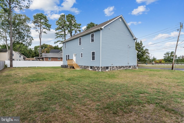 rear view of property featuring central AC unit and a yard