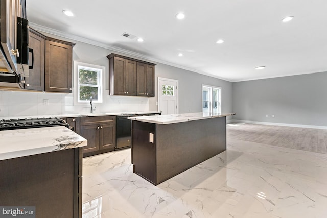 kitchen with appliances with stainless steel finishes, a kitchen island, crown molding, dark brown cabinetry, and sink