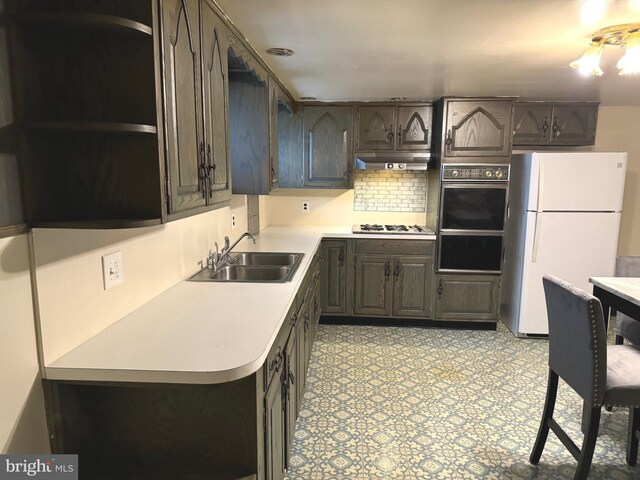 kitchen with stainless steel gas stovetop, backsplash, white fridge, and sink