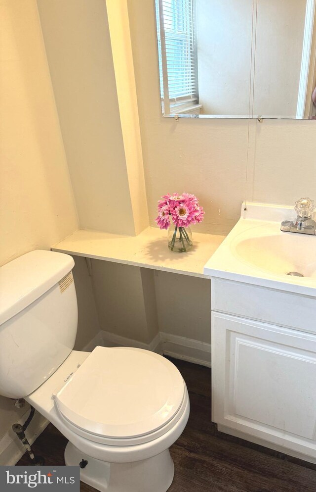 bathroom with wood-type flooring, vanity, and toilet