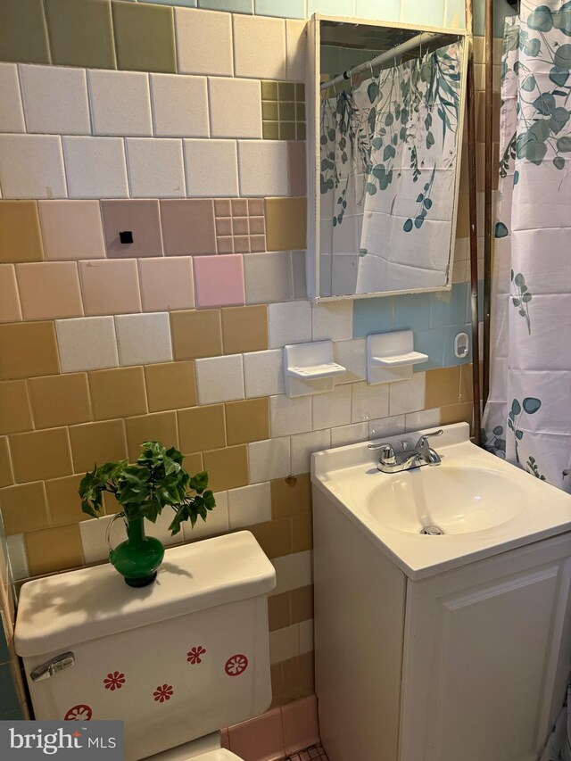 bathroom with tile walls, tasteful backsplash, vanity, walk in shower, and toilet