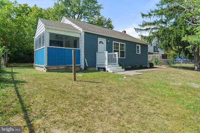view of front of house featuring a chimney, fence, a front lawn, and a shingled roof