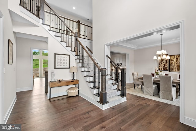 stairs featuring crown molding, an inviting chandelier, and hardwood / wood-style flooring