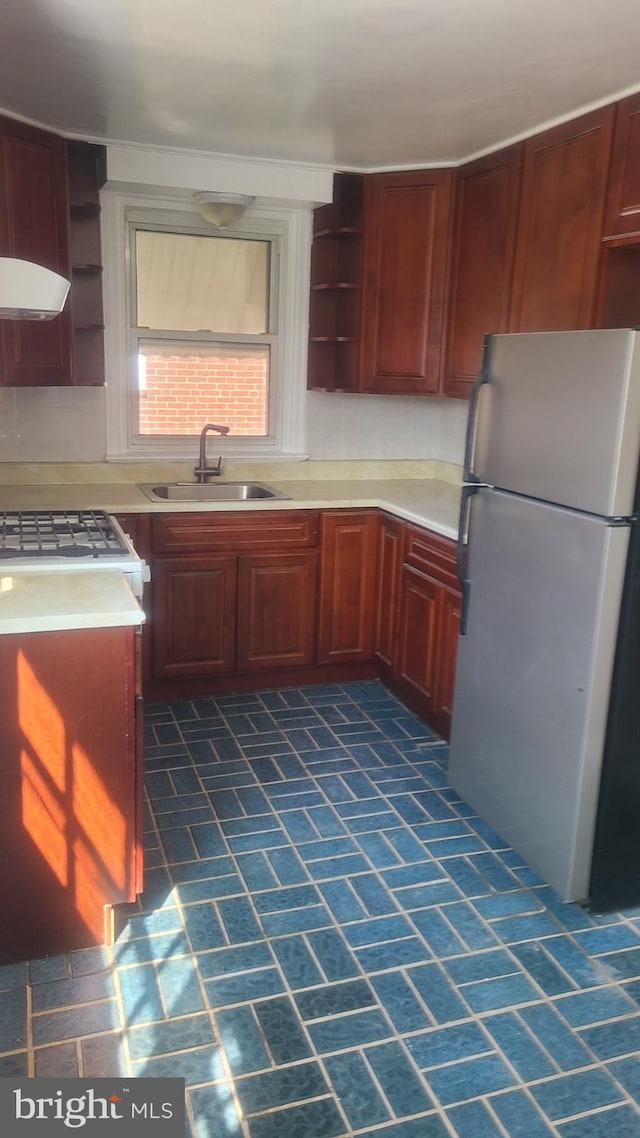 kitchen with white range, stainless steel fridge, and sink