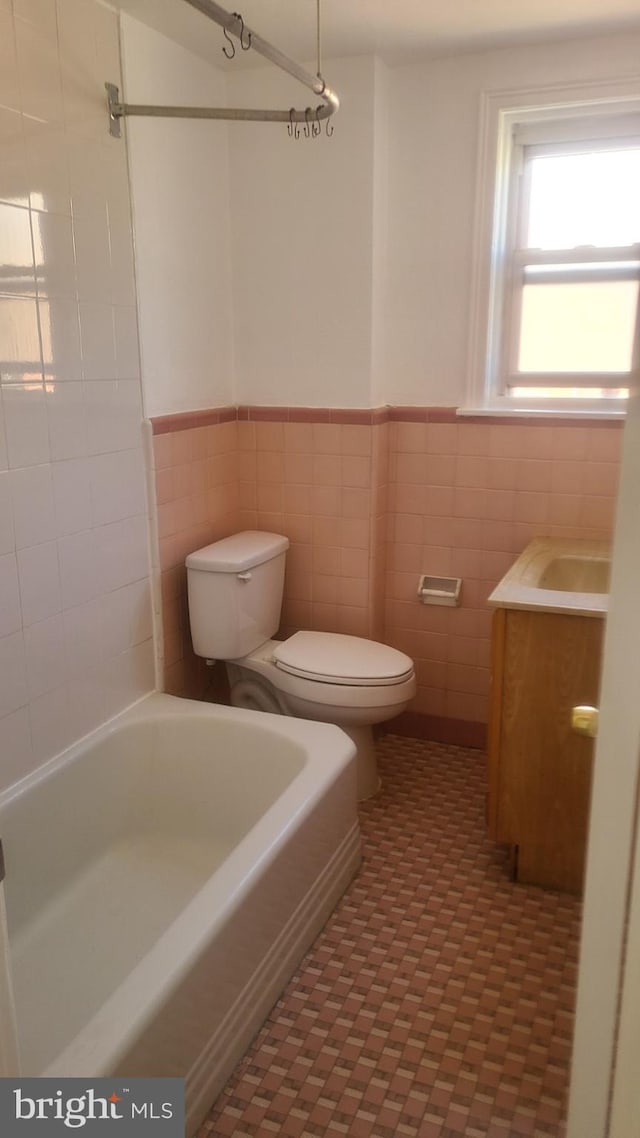 bathroom with vanity, tile walls, and toilet