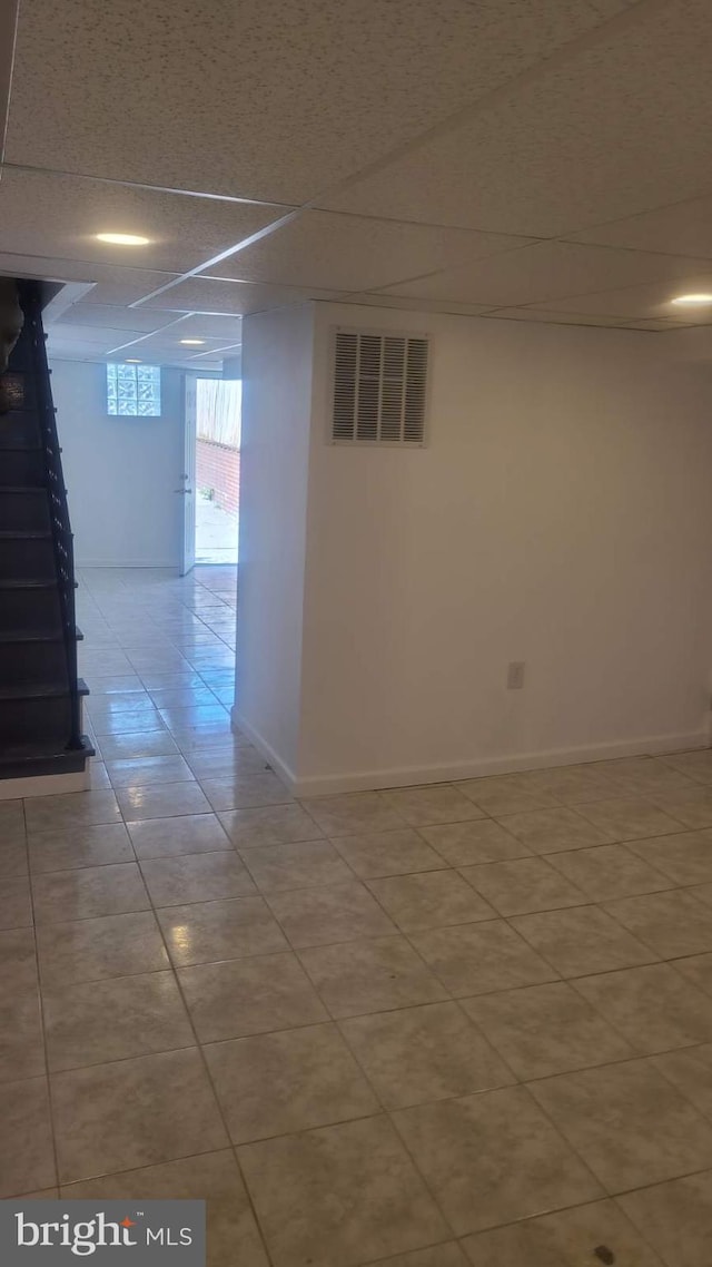 basement featuring a paneled ceiling and light tile patterned floors