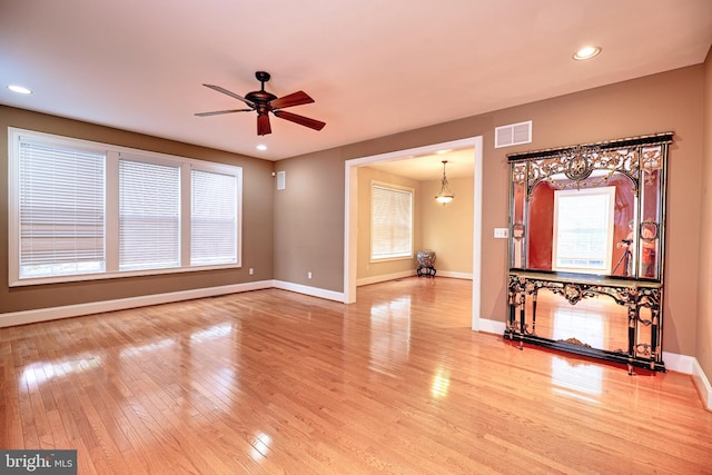 unfurnished living room featuring a wealth of natural light, wood-type flooring, and ceiling fan