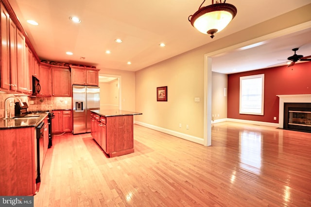 kitchen with light hardwood / wood-style floors, a center island, tasteful backsplash, stainless steel refrigerator with ice dispenser, and ceiling fan